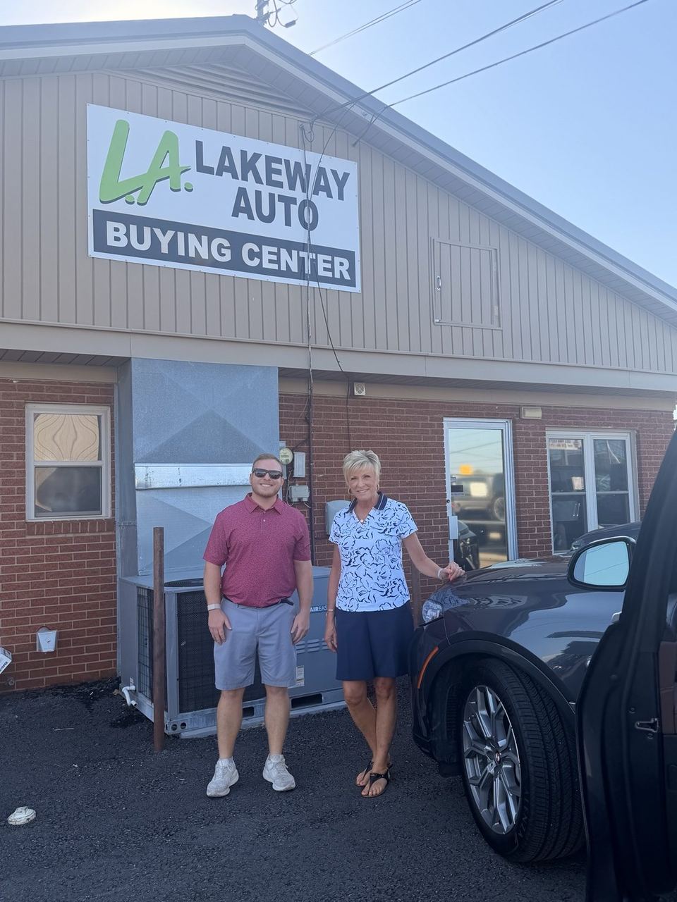 A seller and a Lakeway buyer in front of the Lakeway Auto Buying Center building